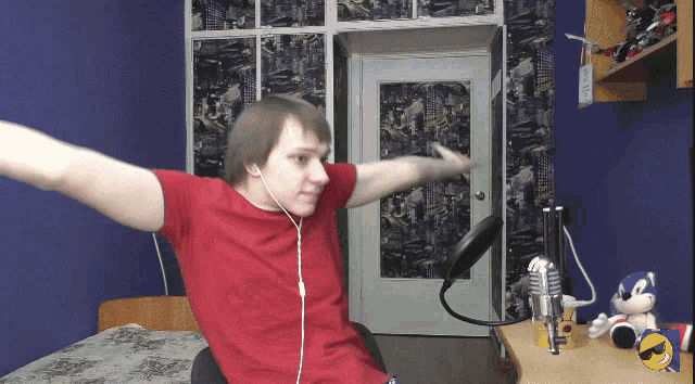 a man in a red shirt is sitting in front of a microphone in a bedroom