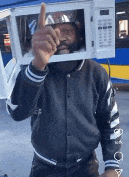 a man with a microwave on his head is giving a thumbs up