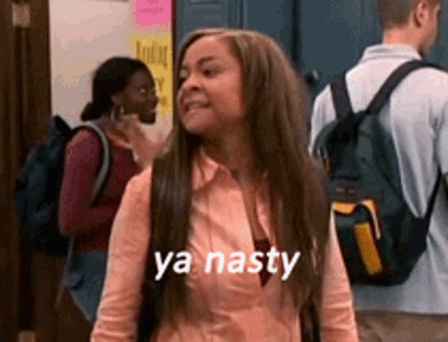 a woman with a backpack says ya nasty in front of a group of people