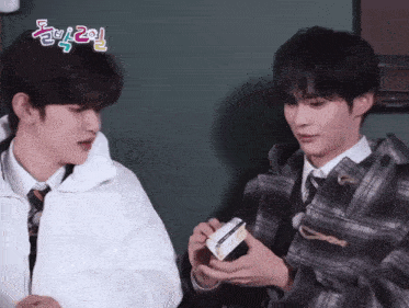 two young men are standing next to each other and one of them is holding a box that says ' a ' on it