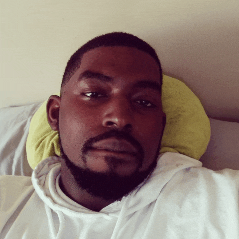 a man with a beard is laying on a bed with his head on a pillow