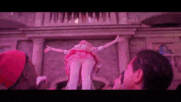 a woman in a pink dress is being lifted in the air by people