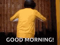 a person in a yellow shirt is dancing in front of a window and the words `` good morning '' are visible .