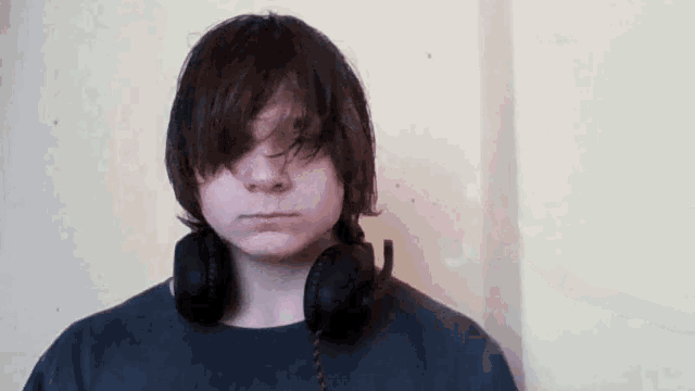 a young man wearing headphones looks at the camera with a serious look on his face