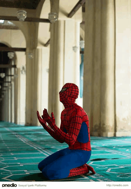 a man in a spiderman costume is kneeling down and praying