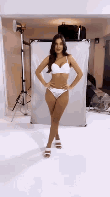 a woman in white lingerie is standing in front of a white backdrop