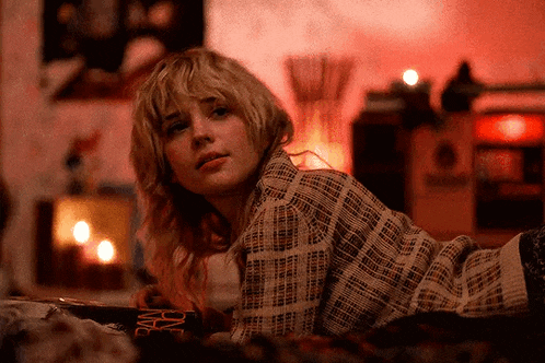 a woman in a plaid shirt is laying on a bed in a room