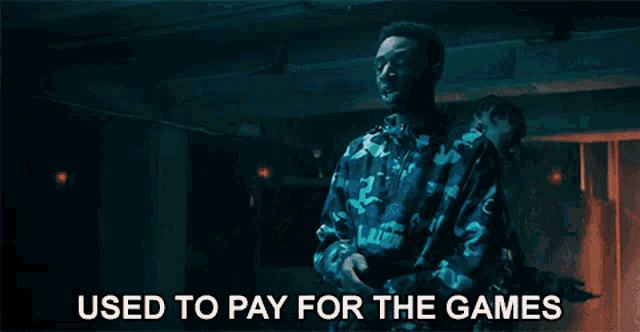 a man in a blue camo jacket is dancing with the words used to pay for the games behind him