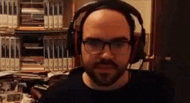 a bald man with a beard wearing headphones and glasses .