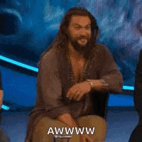 a man with a beard is sitting on a chair and making a face .