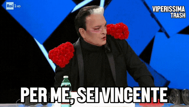 a man with red roses on his shoulders and the words per me sei vincente below him