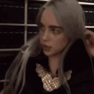 billie eilish is making a funny face while giving a high five .