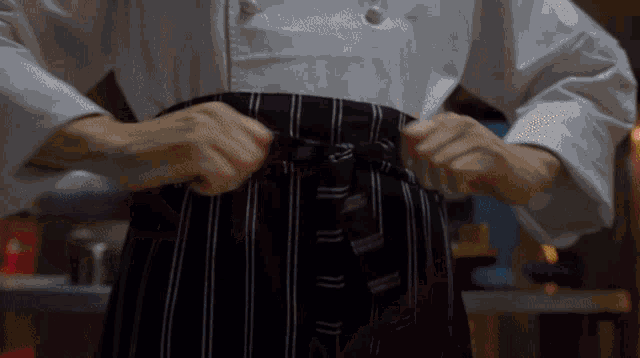 a person in a chef 's uniform is tying their apron