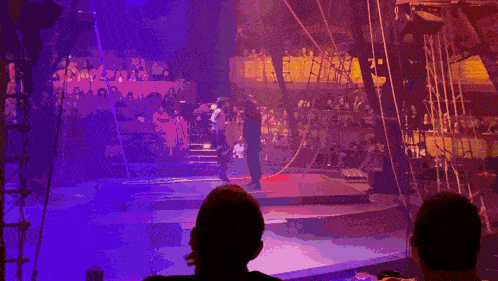 a couple of people watching a circus show with a purple background