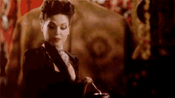 a woman in a black dress is holding a spoon in front of a painting of a horse .