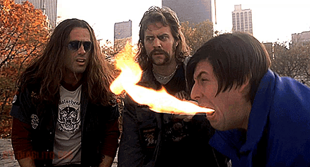 a man wearing a shirt that says motörhead is holding a fire in his mouth