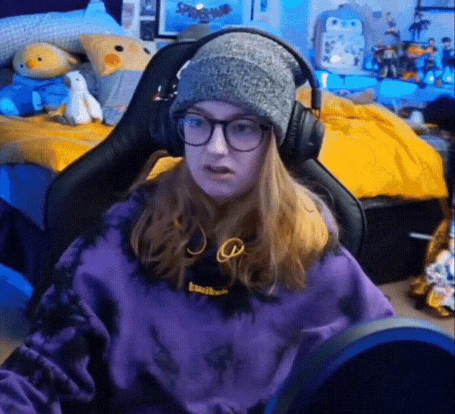 a woman wearing a beanie and headphones is sitting in a chair .