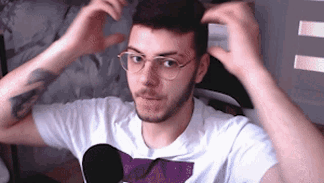 a man wearing glasses and a white shirt with a purple circle on it