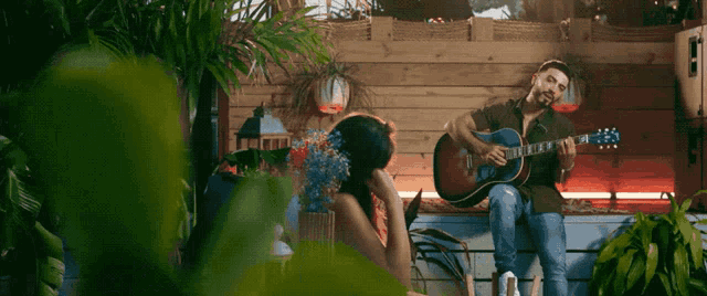 a man playing a guitar next to a woman with flowers in her hair