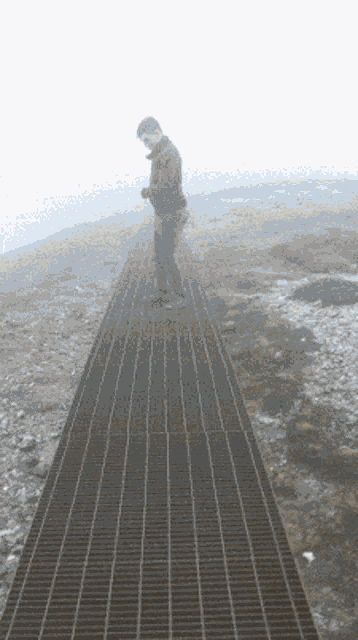 a man standing on a metal walkway looking at his phone