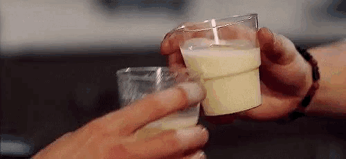 a couple of people are holding glasses of milk in their hands .