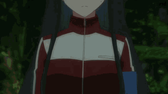 a girl in a red white and black jacket holds her hands to her chest