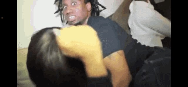a man with dreadlocks is sitting on a couch with a woman .