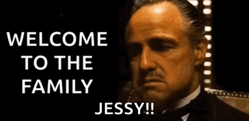 a man with a mustache is smoking a cigarette and says welcome to the family jessy !