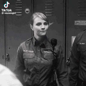 a woman in a police uniform is smiling in a black and white photo .