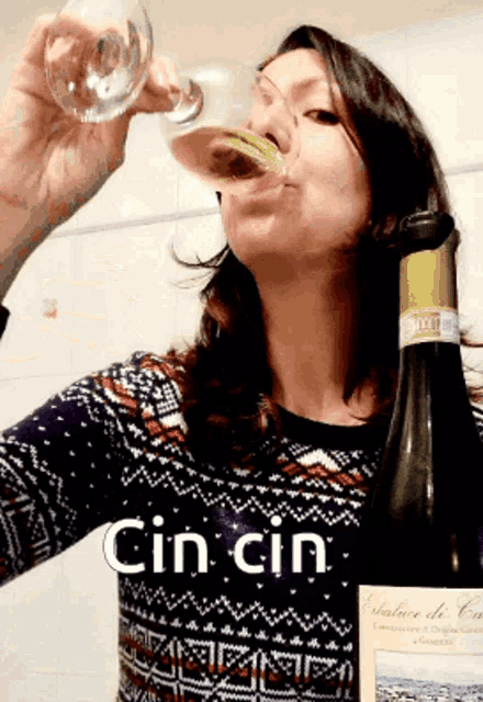 a woman is drinking from a glass next to a bottle of cin cin wine