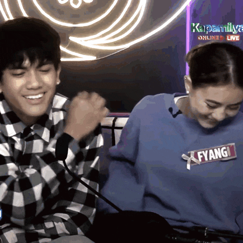 a man wearing a plaid shirt and a woman wearing a blue sweater with fyang on it