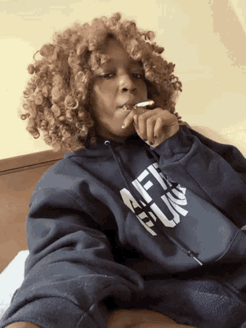 a woman with curly hair is wearing a hoodie that says " fuck "