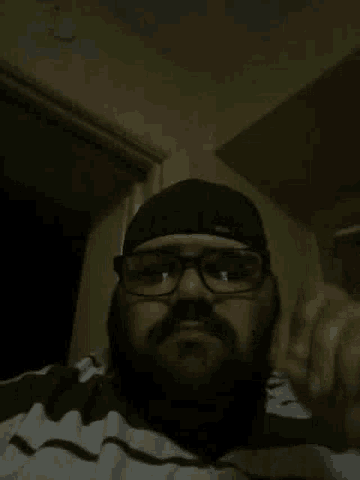 a man with glasses and a beard looks down at something