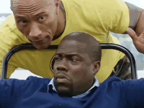 a man in a yellow shirt is leaning over another man in a blue sweater .