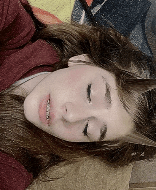 a girl with braces on her teeth laying on a blanket