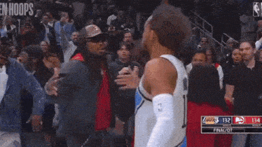 a man is standing next to a basketball player in a crowd during a game .