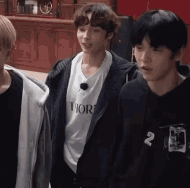 a group of young men are standing next to each other in a room and talking .