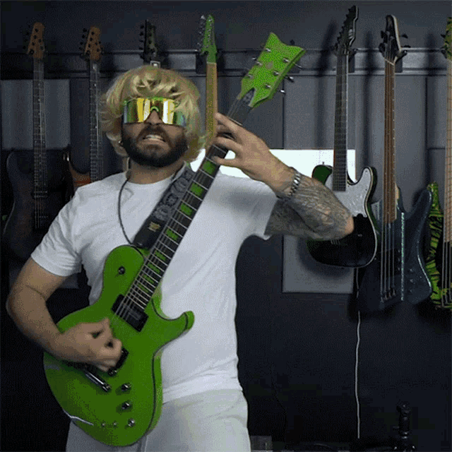 a man is playing a green guitar in front of a row of guitars