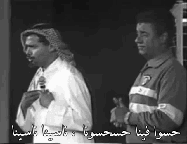 two men are standing next to each other with arabic writing on them