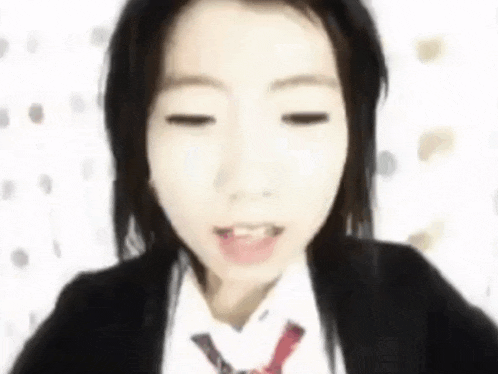 a close up of a woman wearing a suit and tie with her eyes closed
