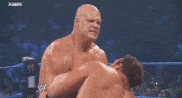 two men are wrestling in a wrestling ring with a sign that says kaine on it .