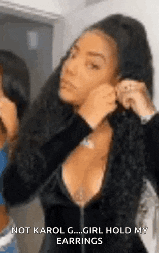 a woman is putting on a pair of earrings while looking at herself in a mirror .
