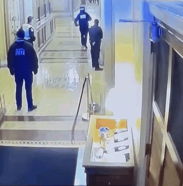 a man in a black jacket with the word mrr on it walks down a hallway