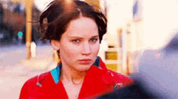 a woman in a red jacket looks at the camera with a serious look on her face