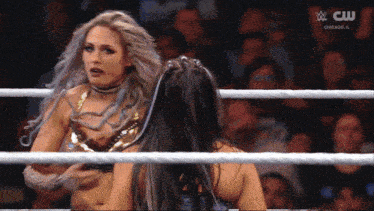 two women in a wrestling ring with a cw logo on the bottom right