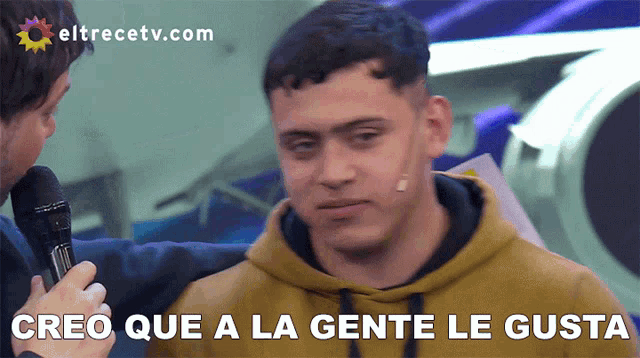 a man talking into a microphone with the words creo que a la gente le gusta behind him