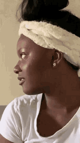 a woman wearing a white headband and earrings looks to her left