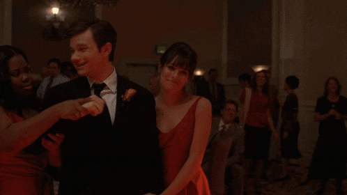 a man in a black suit is dancing with a woman in a red dress