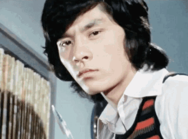 a close up of a man 's face with a striped vest