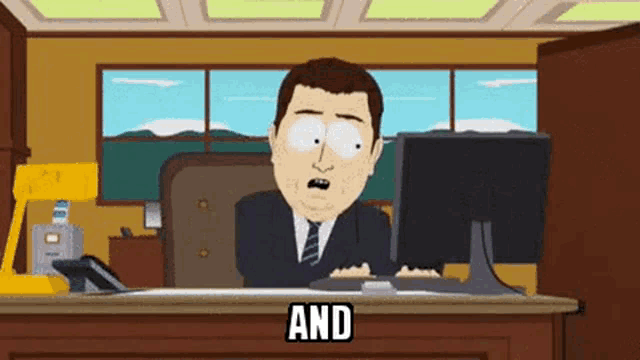 a man in a suit and tie is sitting at a desk with a computer and the word and written on the desk .